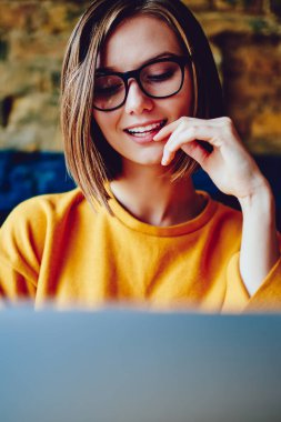 Modern dizüstü bilgisayarda kablosuz internet kullanarak göz koruması sağlayan şık gözlüklü güzel bir genç kadın. Yazılım güncelleyen sevimli çekici kadın grafik tasarımcısı.