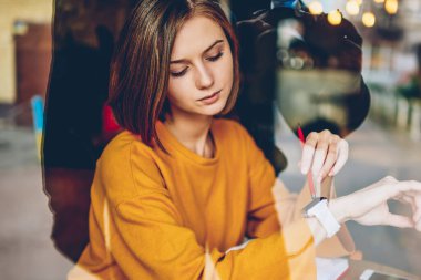 Sonraki toplantı rahat kafeterya iç dinlenme dijital dizüstü bilgisayar, oturmak için zaman yönetimi modern smartwatch görünümünü bakarak şık saç kesimi ile meşgul iş kadını