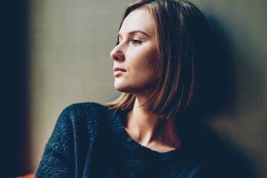 Düşünceli genç kadın rahat coworking alanda dinlenme pencereden dışarı bakarak siyah casual kıyafet giymiş. Smartphone geleceği üzerine düşünme elinde durulması hipster kızla