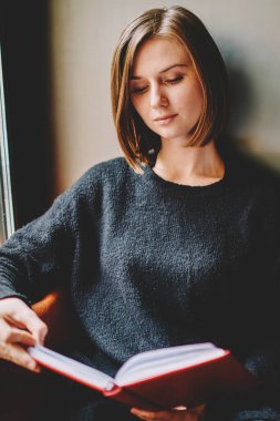 Rahat coworking yerde dikkatle ilginç kitap okuma dalgın akıllı genç kadın. Zeki konsantre öğrenci bilgi kapalı dinlenme edebiyat ders kitabından öğrenme