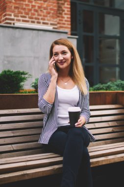 Tasasız genç hippi kız moda kıyafetleri giyer uluslararası arama için akıllı telefon uygulaması ile iletişim kurar, pozitif kadın cep telefonuyla konuşur ve dışarıda internete bağlanır.