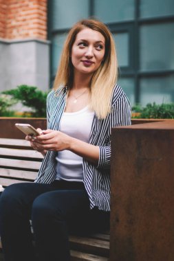 Kenar mahallelerdeki bankta otelden yer ayırtırken yan yan bakan beyaz bir kadın. Elinde yeni modern akıllı telefon tutan çekici bir hippi kız. Açık havada uygulamayla sohbet ediyor.