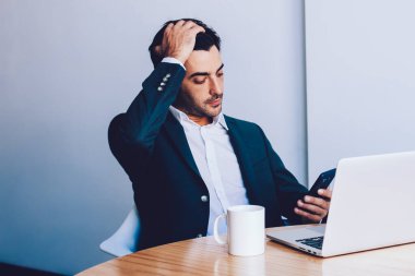Şaşkın genç milenyum girişimcisi şirket yöneticisinin e-postasını okurken elinde netbook cihazıyla düşünceli bir adam teknolojiyi kullanarak sunuma hazırlanıyor.