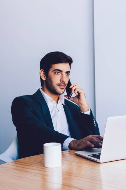 Ciddi bir işadamı, 4G bağlantısı ve modern teknoloji kullanarak anlaşma yapmak için banka hizmetini arıyor. Yakışıklı Hintli adam içeride telefon görüşmesi yapıyor. Masada oturuyor.