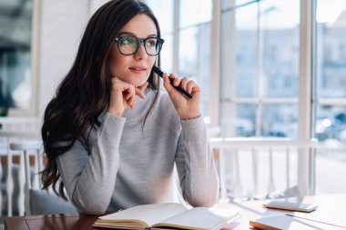 Yoğunlaşmış hippi kız, düşünceli bakışlar atıp ev ödevlerini düşünüyor, düşünceli zeki bayan öğrenci öğreniyor ve önemli sınavlara hazırlanıyor. Üniversite kafesinde otururken yaşanan soruna şaşırıyor.