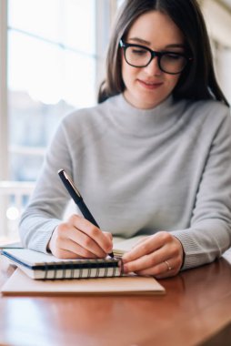 Gözlüklü zeki bayan öğrenci üniversite kampüsünde eğlenirken organizasyon planına dikkat çekiyor, genç hippi kız ders kitabında ödevini evde dizüstü bilgisayarla yapıyor.