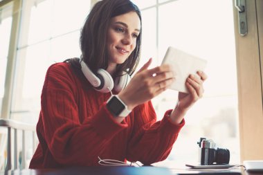 Kafkasyalı hippi kız, arkadaşı beklerken portatif bilgisayarla video izleyerek eğleniyor. Genç, gülümseyen kız oyuncu öğrenci, dijital tablet uygulaması ile bir sonraki seviyeyi geçiyor.
