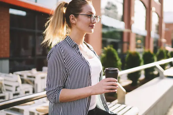 İçki ve gençlik hayatı kavramı, elinde kahve fincanı tutan, şehir bankında oturan, güneşli günün keyfini çıkaran, neşeli gözlüklü, kaygısız hippi kız.