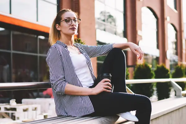 Üniversiteden önce sabah kahvesini yudumlayan düşünceli genç bir kız öğrencinin portresi şehir dışında otururken şık giyinmiş, poz veren ve bankta kameraya bakan çekici bir genç.