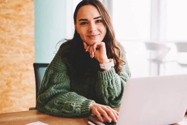 Yarım uzunluk portre çekici yaratıcı öğrenci modern dizüstü bilgisayar başında oturan kamera gülümseyen bağlı 4g internet. Dijital netbook ofis iç çalışma neşeli kadın serbest meslek