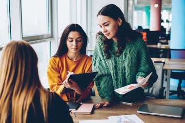 Yetenekli öğrencilerin birbirleri ile yeni oluşturmak için fikirleri hakkında iletişim Üniversitesi'nde beyin fırtınası sırasında çizimler tasarlayın. Birlikte kendi moda katalog Office geliştirmeye çalışan genç kadınlar