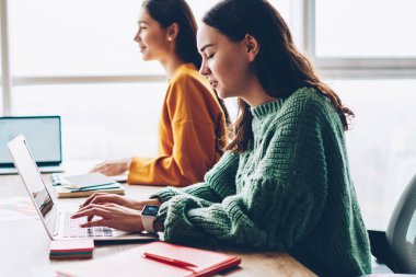Klavye masaüstü tasarım projesi için fikirler tartışırken meslektaşları wich birlikte oturan kablosuz internet'e bağlı modern netbook aygıt bilgileri yazarak dalgın kadın metin yazarı