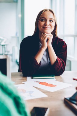 Studio iç tasarım ile masaüstünde oturan beyin fırtınası sırasında gülüyor sarı saçlı Sevimli gülümseyen genç kadın skeçler. Güzel öğrenci proje tartışılması sırasında yeni fikirler dinleme