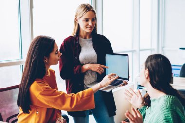 Arama bilgi için dizüstü bilgisayar ve internet kaynakları kullanarak tasarım proje üzerinde üç yetenekli öğrenciler teamworking. Office Çevrimiçi sunu üzerinde birlikte yaratıcı moda çalışanlar