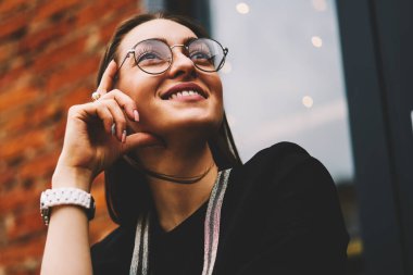 Gülümseyen güzel genç uzağa bakarak ve uygulanması için başarılı fikirler düşünmeye trendy Eyewear closeup görüntüsü. Büyüleyici olumlu hippi kız zevk eğlence anda kentsel ayarı