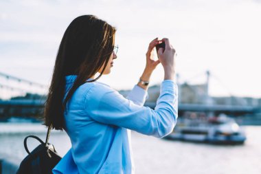 Kadın Gezgin Nehri Köprüsü'nde City, gezinme genç hippi kız cep telefonu eğlence sırasında sıcak akşam zevk video çekim smartphone kullanarak resim yapma kayıtsızca giyinmiş