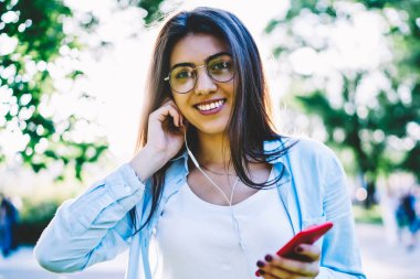 Varoluş rahat kıyafet için kulaklıklar koymak mutlu hippi kız portresi mükemmel şarkı favori müzik, neşeli kız öğrenci dinleme şarkılar kameraya bakarak akıllı çalma listesinden tadını çıkarın