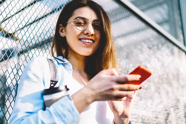 Gözlük bloglama sosyal ağlar açık havada serbest zaman sahip kız öğrenci gülümseyen, neşeli genç kadın manifatura mesaj mobil arkadaşlarınızla sohbet üzerinde sokakta duran tarifeler ile memnun