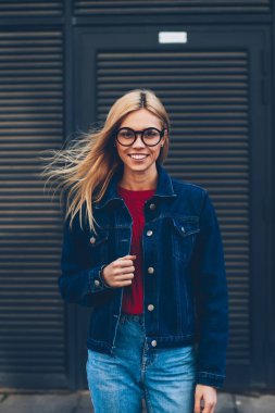 Mutlu hippi kız zekâ sarı saçlı ve optik gözlükler kameraya poz portresi. Reklam alanı siyah promosyon zemin üzerine ayakta gözlük neşeli genç kadın giyinmiş