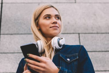 Post modern kulaklıklar yeni müzik yayımlama ile çekici kadın blogger görünümünü aşağıda Web sitesinde 4 g internet bağlantısı ayakta Kapılarımızın promosyon gri arka plan üzerinde üzerinden dijital smartphone