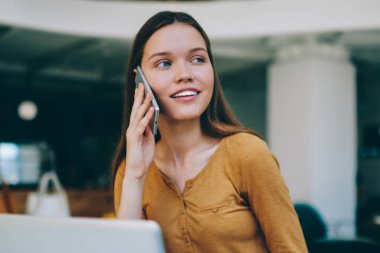 Kafeteryada çalışırken, müşteri hizmetleri ile sohbet için yeni bir akıllı telefon uygulaması aracılığıyla arayan başarılı, tatlı gülüşlü ve başarılı bir kadın yazılım geliştirici.