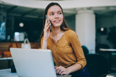 Kafeteryada çalışırken, müşteri hizmetleri ile sohbet için yeni bir akıllı telefon uygulaması aracılığıyla arayan başarılı, tatlı gülüşlü ve başarılı bir kadın yazılım geliştirici.