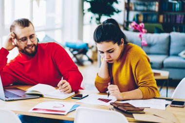 Genç evlilik planlama bütçe geliri modern teknolojiyi kullanarak dairede otururken, hipster kadın ve erkek araştırma ve bilgi analizi yaparken birlikte faturaları kontrol ediyorlar.