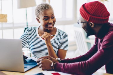 Gülümseyen Afro-Amerikan kadın meslektaşı ile birlikte çalışma alanı projesinde işbirliği yapıyor, başarılı koyu tenli erkek ve kadın tasarımcılar çalışma sürecinde yaratıcı fikirleri tartışıyorlar.