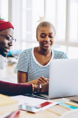 Koyu tenli yetenekli hippi kız arkadaşının internet defterinde güncelleme yapıyor. Ev içinde oturan Afro-Amerikan çift bilgi aramak ve rezervasyon yapmak için dizüstü bilgisayar kullanıyor.