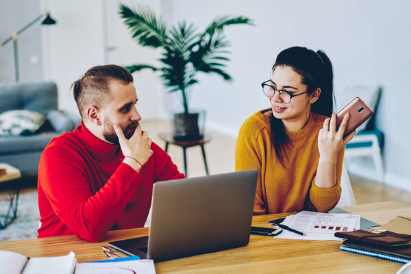 Веселые мужчины и женщины обсуждают идеи для отдыха с использованием современных технологий для исследований, молодая пара влюбленных проверяет счета и счета за семейный бюджет, используя мобильный телефон и нетбук-банкинг