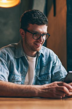 Gülümseyen hippi, internet bağlantısı ve modern mobil uygulama kullanarak arkadaşından olumlu e-posta okuyor, sosyal ağlarda cep telefonuyla komik videolar izleyen başarılı bir adam.