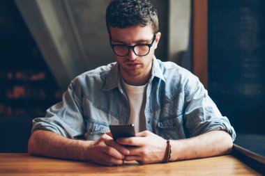 Milenyum erkek blogcusu, akıllı telefon aygıtında iletişim uygulaması kullanarak göz koruması sağlayan metin mesajı yazıyor. İnternette bilgi arayan yakışıklı hippi adam.