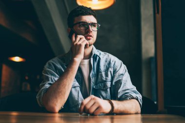 Konsantre olmuş ciddi bir adam, hesap bakiyesini kontrol ettiği için operatöre telefon ediyor. İnternetteki akıllı telefonu kullanıyor. Gözlüklü hippi adam içeride iş arkadaşıyla telefon görüşmesi yapıyor.