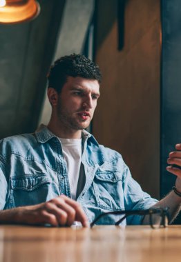 Kafası karışmış hipster adam iş arkadaşından gelen kötü haberlerle e-postayı okuyor. Akıllı telefon cihazında sohbet etmek için başvuru kullanıyor. Konsantre olmuş adam, sosyal ağlarda cep telefonuyla video izlemekle kafayı bozmuş.