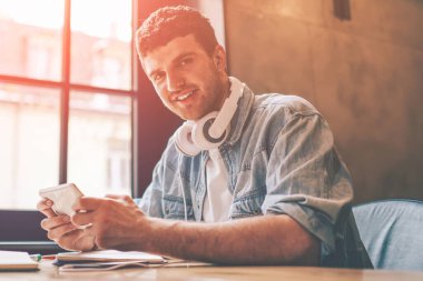 Elektronik kulaklıklı neşeli hippi adamın portresi dijital tablete yeni oyun yüklerken kameraya bakıyor, olumlu adam blogcusu dokunmatik ped ile takipçilerle iletişim kuruyor.