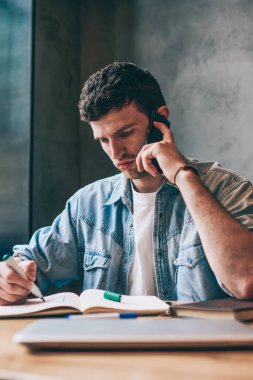 Ciddi milenyum erkek mimarı, iletişim için 4G internet kullanarak iş arkadaşına danışmanlık yapıyor. Genç yaratıcı tasarımcı, akıllı telefon cihazıyla arkadaşıyla konuşurken eskiz çiziyor.