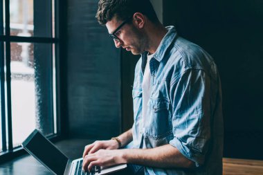 Kafkas erkek serbest çalışan kafeterya penceresinin yanında oturuyor ve modern laptop uygulamasında yeni bir makale yazıyor, genç blogcu kablosuz interneti tarıyor ve sosyal ağlardaki profili güncelliyor