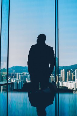 Formal giyim ayakta kendi şirketin ofis iç ve metropolis sahne açık havada zor iş günü sonra akşam zevk pencereden dışarı arıyor işadamı silüeti geri