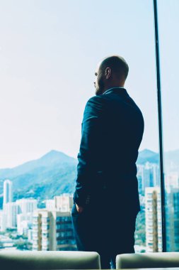 İşadamı kapalı ofis modern iç ayakta ve kendi şirket geliştirmek için yeni fikirler üzerinde düşünme resmi elbise giymiş. Windown dışında seyir ve metropolis sahne zevk gurur ceo