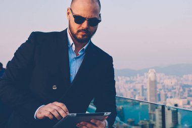 Finansal haber modern binanın çatı terasta metropolis manzaralı dinlenme dijital tablet ile internet web sitesinde gezinirken şık güneş gözlüğü emin icra müdürü