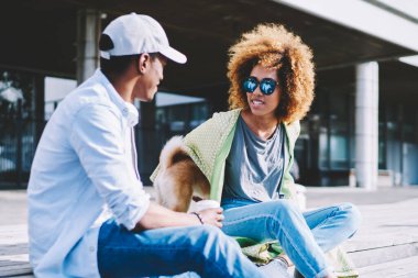 Koyu tenli, evcil hayvanlı en iyi arkadaşlar ahşap merdivenlerde oturup sohbet ediyorlar ve şehir ortamında boş zamanlarının tadını çıkarıyorlar. Afro-Amerikan gençleri, boş zamanlarını dışarıda geçiriyorlar.