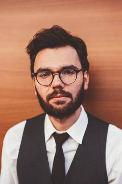 Görüntü düzeltmesi için şık gözlüklü beyaz adamın portresi. Reklam alanında duvarın yanında duruyor ve kameraya bakıyor. Moda kıyafetleri içinde, açık hava modasına uygun genç adam.