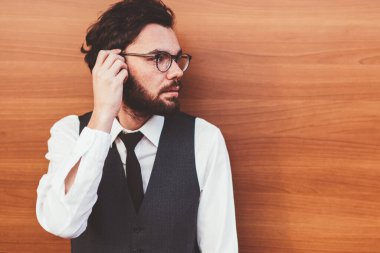 20 'li yaşlarda, şık giyinmiş genç beyaz adam reklam alanında duvarın yanında dikilirken yüzünü çeviriyor. Modaya uygun yelekli esmer adam dışarıda vakit geçiriyor ve sokakta arkadaşını bekliyor.