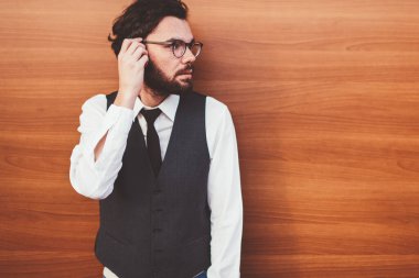 20 'li yaşlarda, şık giyinmiş genç beyaz adam reklam alanında duvarın yanında dikilirken yüzünü çeviriyor. Modaya uygun yelekli esmer adam dışarıda vakit geçiriyor ve sokakta arkadaşını bekliyor.