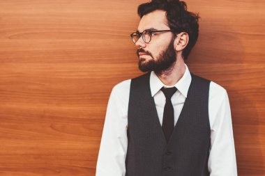 Gözlüklü, gözlüklü, gözlüklü bir hippi. Tanıtım arkaplanının yanında duruyor ve dışarıda arkadaşını beklerken başka tarafa bakıyor. Reklam için fotokopi alanının yanında modaya uygun giyinmiş genç bir adam.