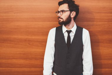 Gözlüklü, gözlüklü, gözlüklü bir hippi. Tanıtım arkaplanının yanında duruyor ve dışarıda arkadaşını beklerken başka tarafa bakıyor. Reklam için fotokopi alanının yanında modaya uygun giyinmiş genç bir adam.