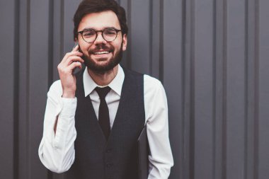 Olumlu uluslararası telefon görüşmeleri sırasında kameraya bakan neşeli hipster adamın yarım boy portresi. Gözlüklü adamın tanıtım alanında gezinme bağlantısını kullanması.