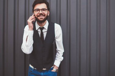 Olumlu uluslararası telefon görüşmeleri sırasında kameraya bakan neşeli hipster adamın yarım boy portresi. Gözlüklü adamın tanıtım alanında gezinme bağlantısını kullanması.