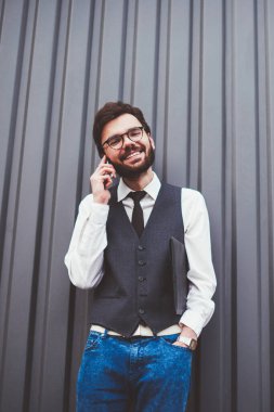 Gülümseyen hippi adam telefon uygulaması aracılığıyla arkadaşa telefon ediyor. Reklam alanında gezinme bağlantısını kullanıyor. Modayı takip eden giysili mutlu beyaz adam fotokopi alanı yakınlarında akıllı telefon konuşması yapıyor.