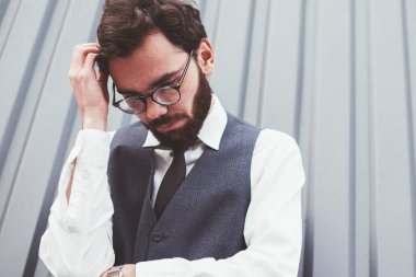 Moda kıyafetleri içinde düşünceli bir hippi, reklam metni için fotokopi alanının yakınında kafa yoruyor, düşünceli bir adam reklam alanının yakınında vakit geçiriyor, dışarıda arkadaşını beklerken düşünüyor.